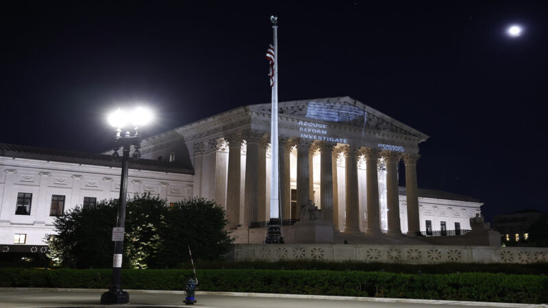 A photo of the Supreme Court with the words "recuse, reform, investigate" and an upside down American flag projected onto it.